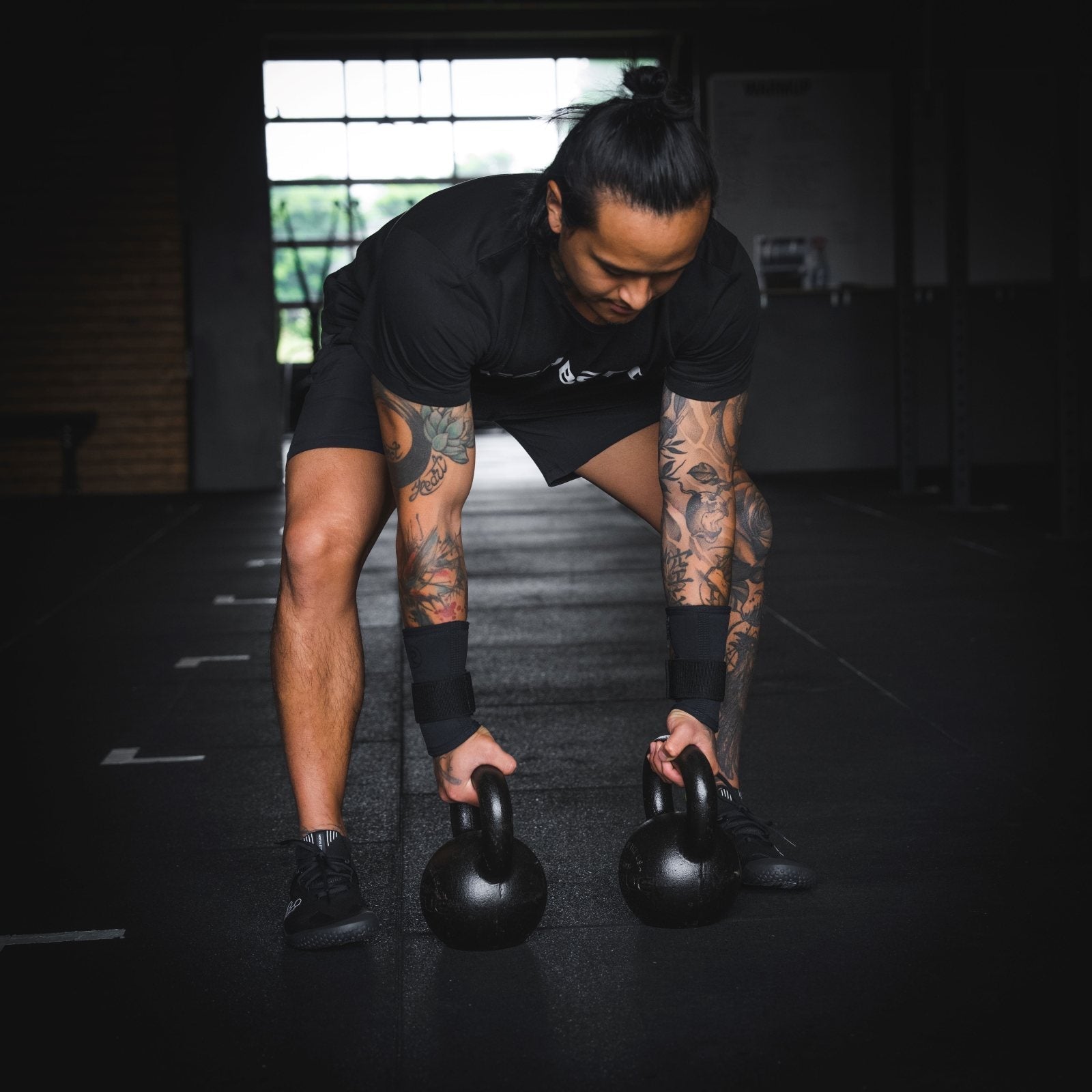 CrossFit Athlete lifting kettlebells in the gym while wearing Rehband Wrist supports